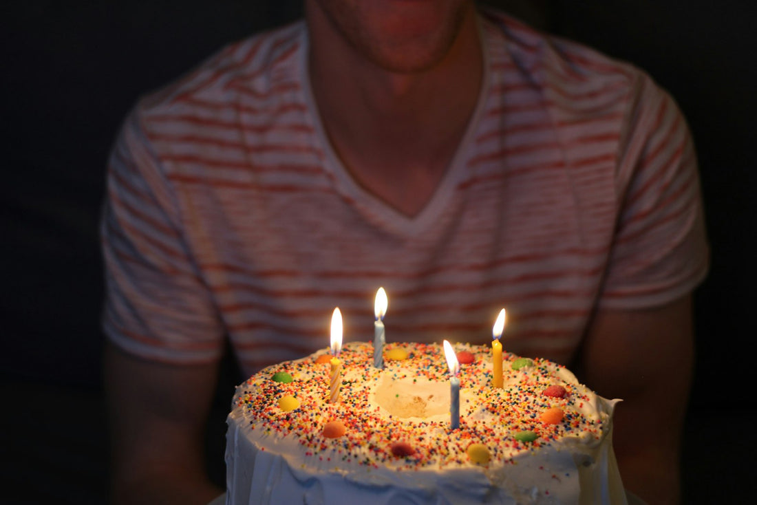 Man smiling at a birthday cake with lit candles on his birthday