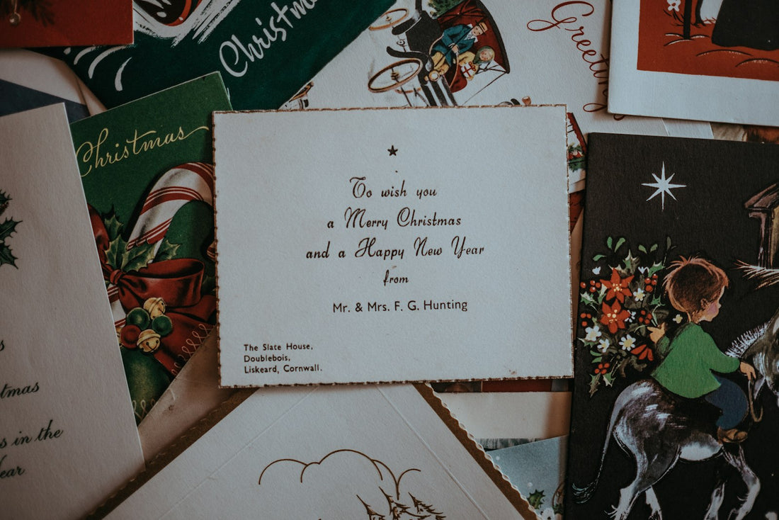 Person at a table writing messages inside a stack of Christmas cards