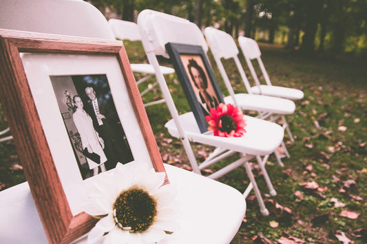 Reserved ceremony chairs with framed photos honoring deceased loved ones at a wedding