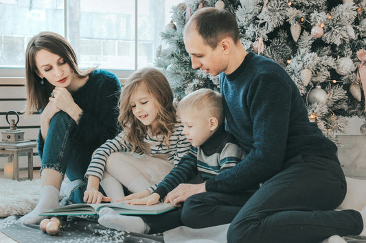 Family sitting together by the Christmas tree enjoying a holiday tradition