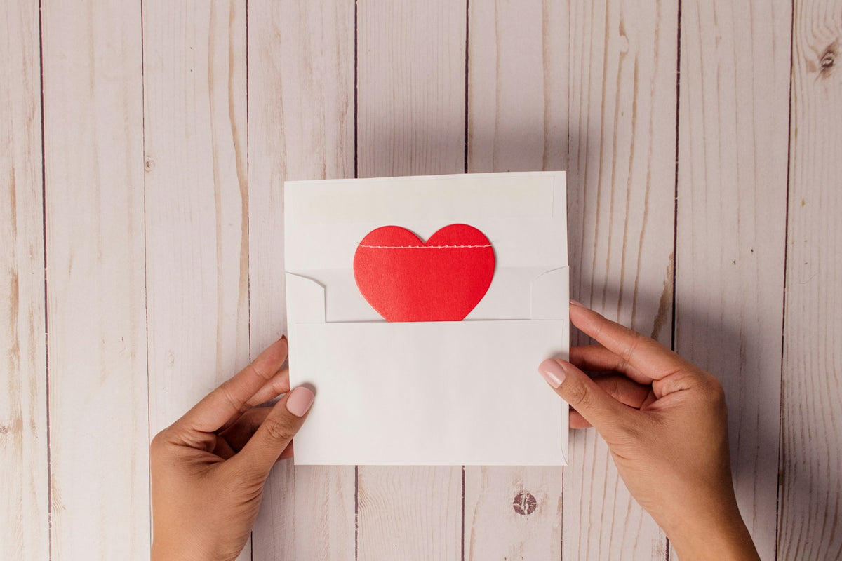 Hands holding a handmade Valentine's card decorated with a red heart
