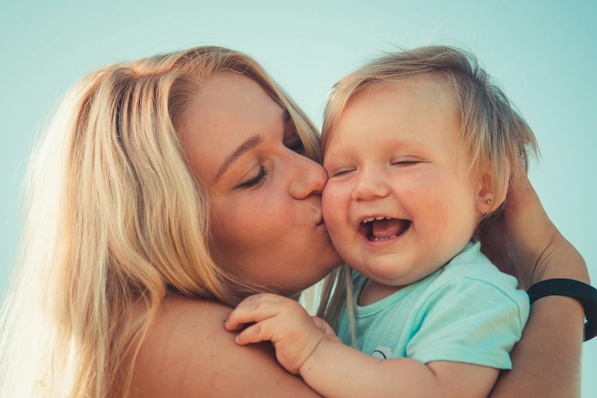 Mom kissing her toddler, celebrating her first Mother's Day together