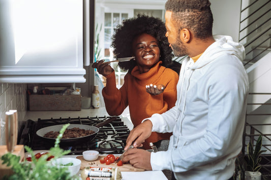 Husband and wife laughing while cooking together