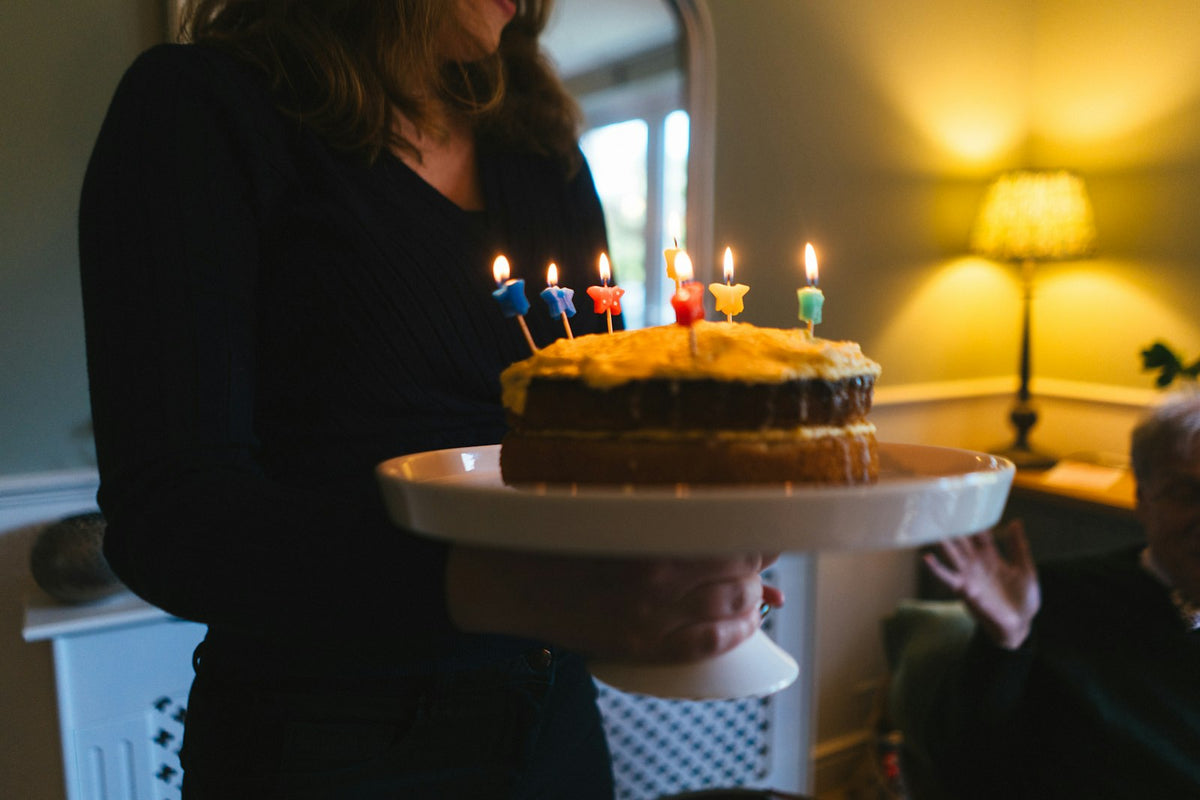Smiling woman holding a birthday cake with lit candles for her 50th