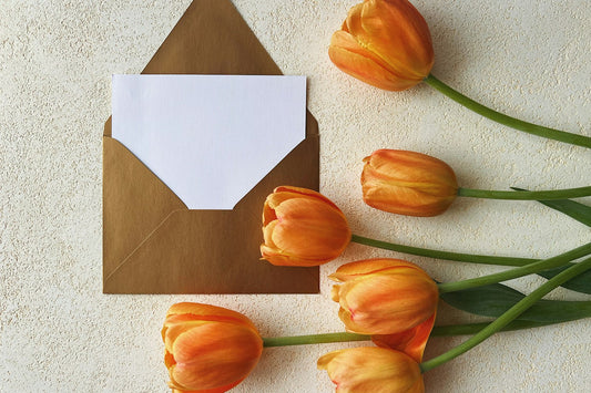 Mother's Day card and envelope beside a bunch of orange tulips