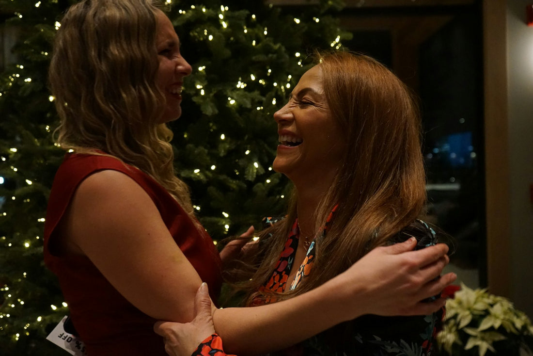 Mother and adult daughter hugging by the Christmas tree