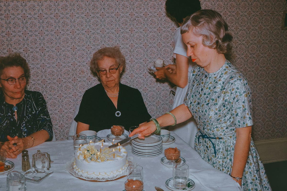 Older women smiling around a birthday cake at an 80th birthday celebration