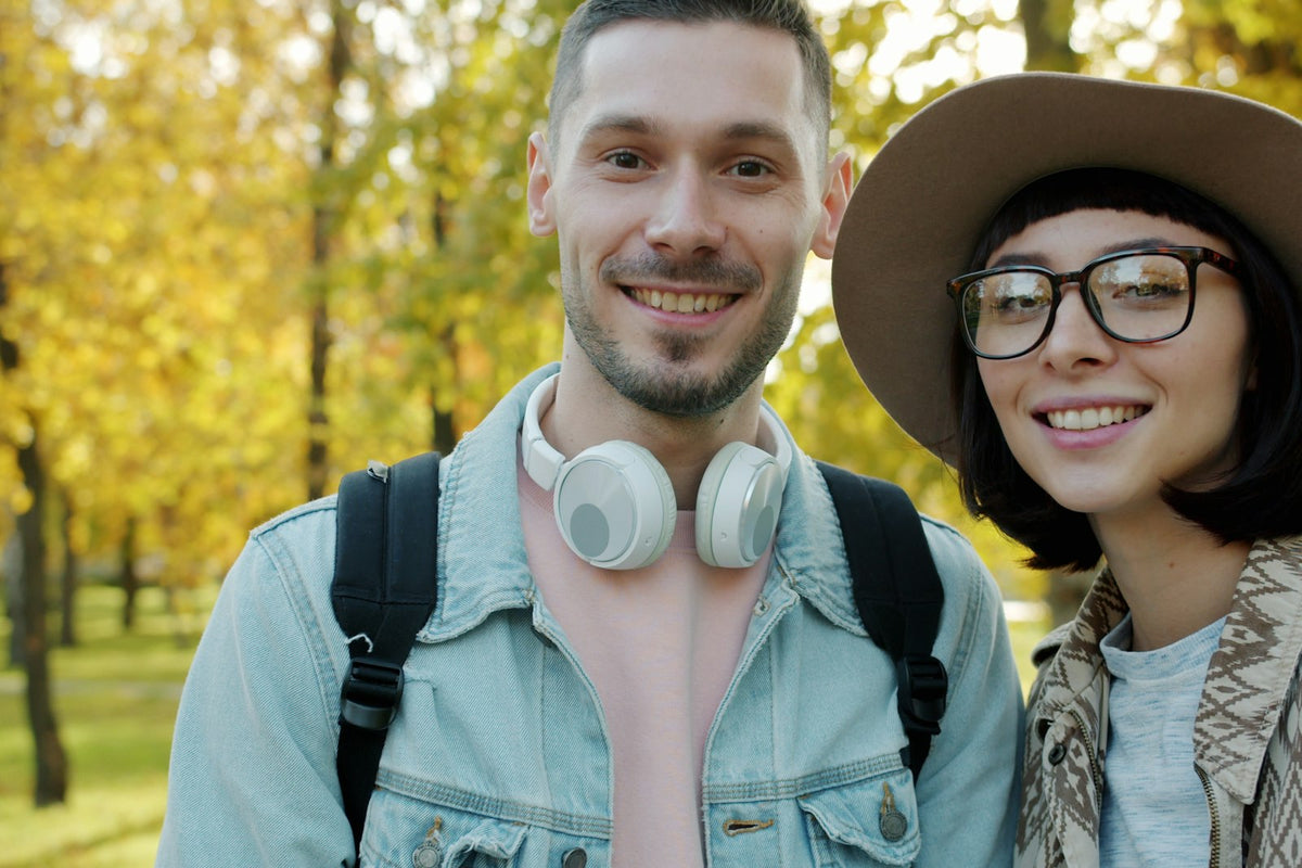 Smiling couple outdoors, one wearing headphones