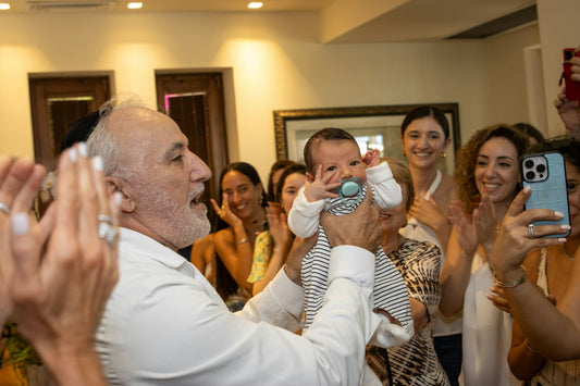 New grandfather holding his newborn grandchild surrounded by smiling family